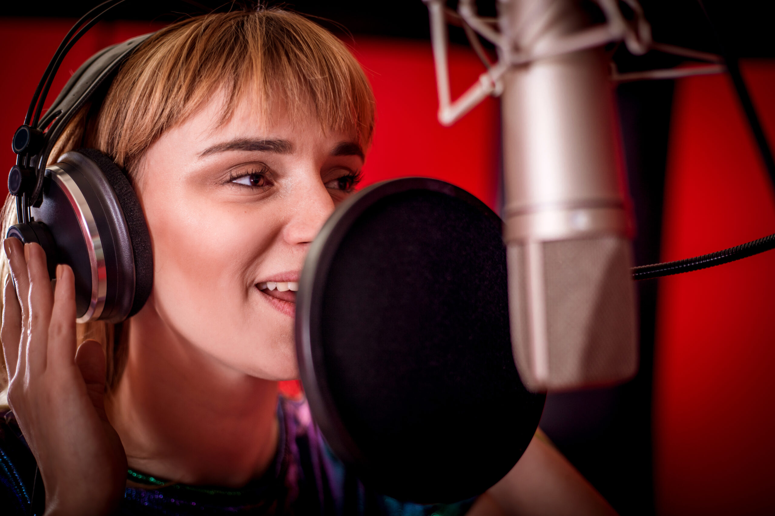 Female singer with microphone recording a song in music studio