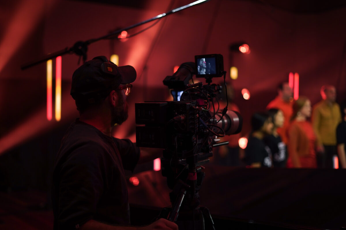 Crew member behind a camera with red lights